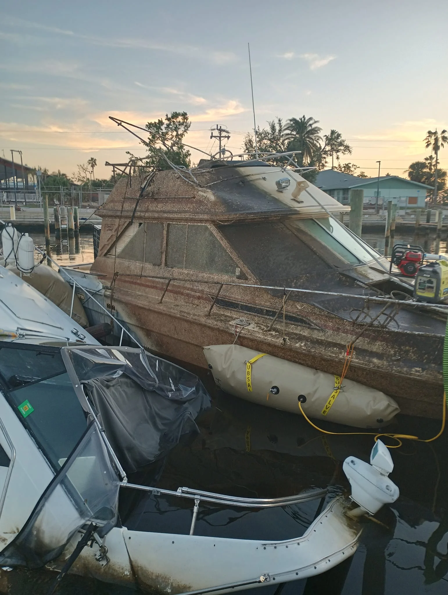 Weathered cruiser with flotation bags beside another vessel
