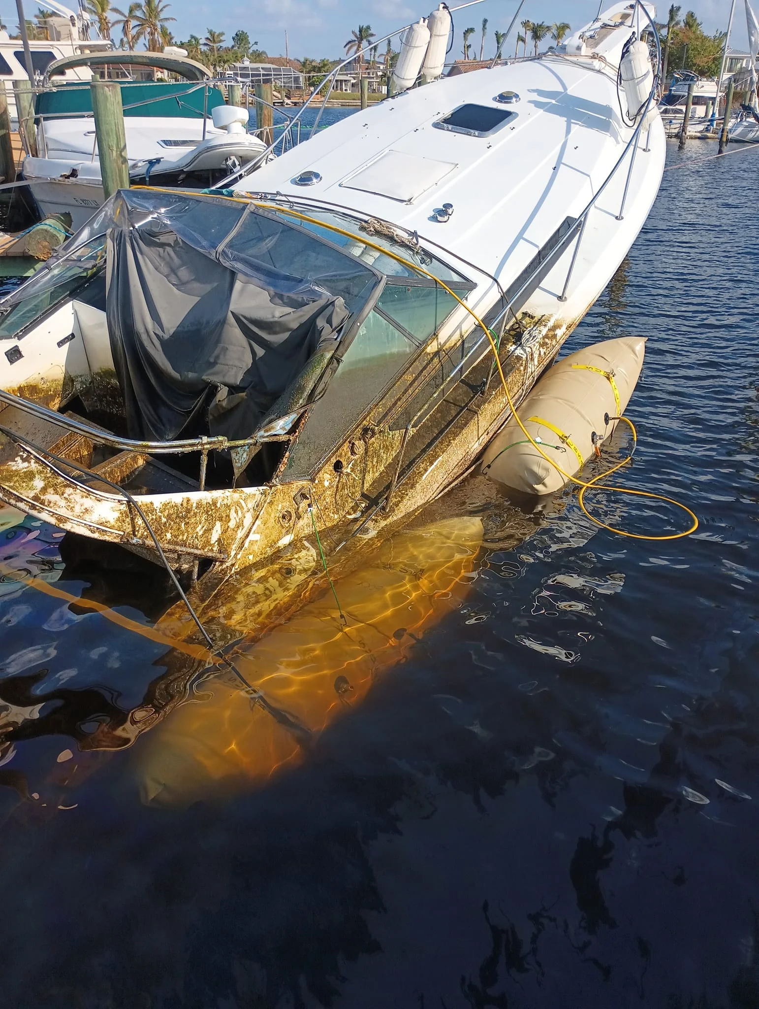 Damaged cruiser alongside a dock with a flotation bag