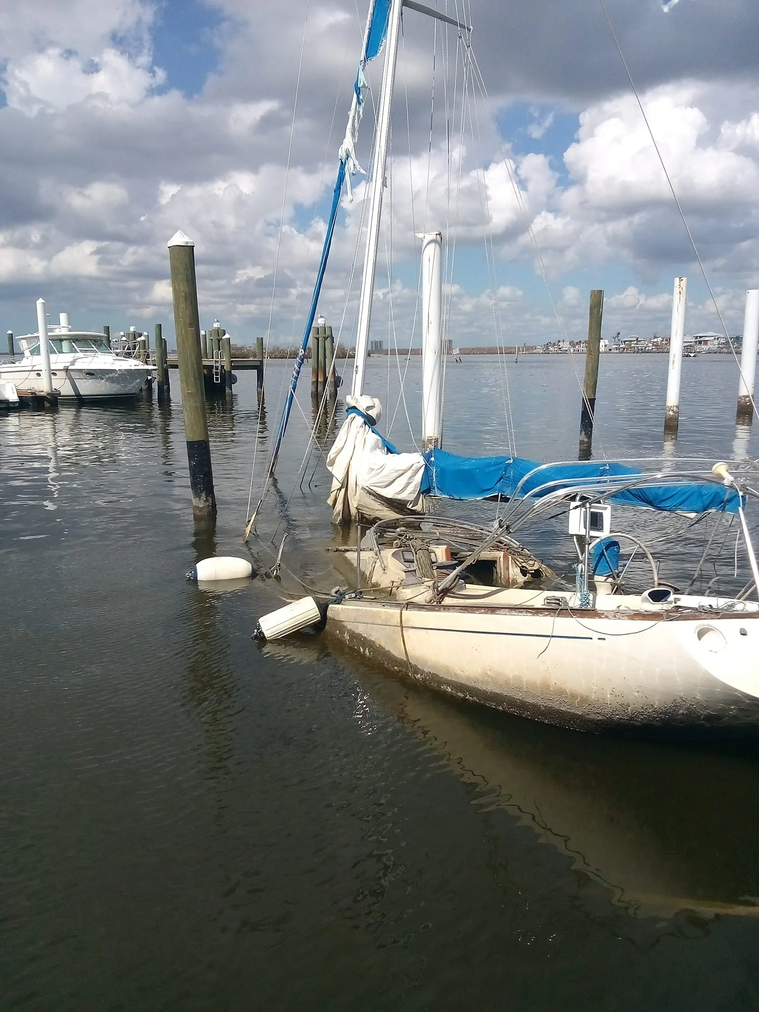 Sailboat sitting low in the water beside marina pilings