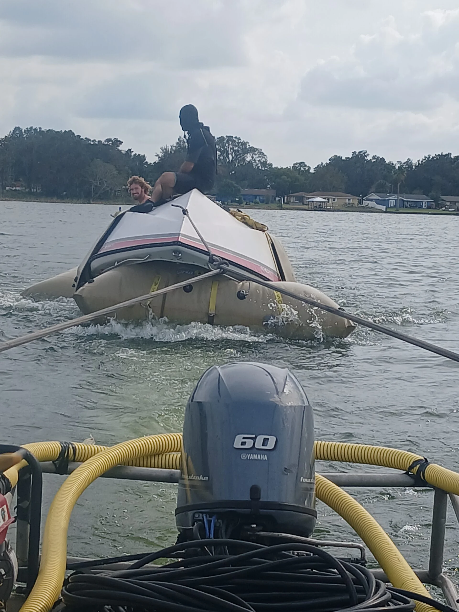 Crew beside a small hull supported by flotation bags