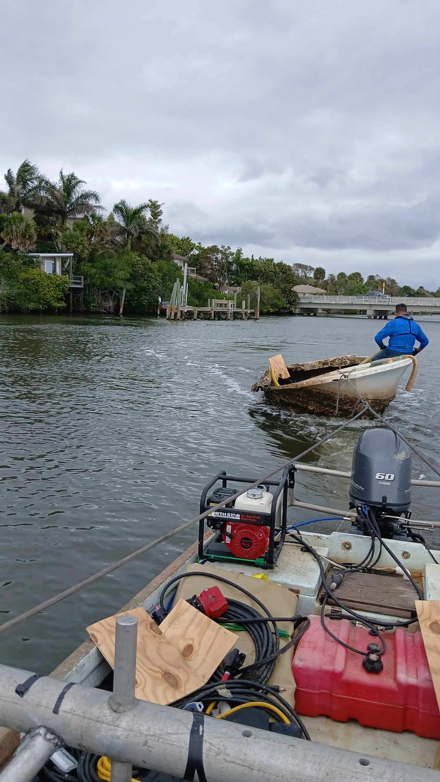 Partially submerged small hull beside recovery equipment