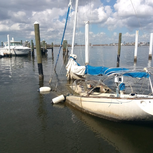 Sailboat sitting low in the water beside dock pilings