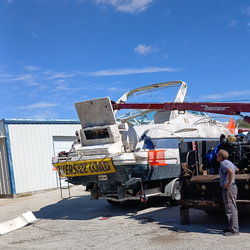 Crew and lifting equipment beside the stern of a damaged cabin boat