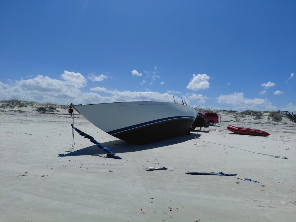 Grounded sailboat resting on sand with its mast lying beside the hull