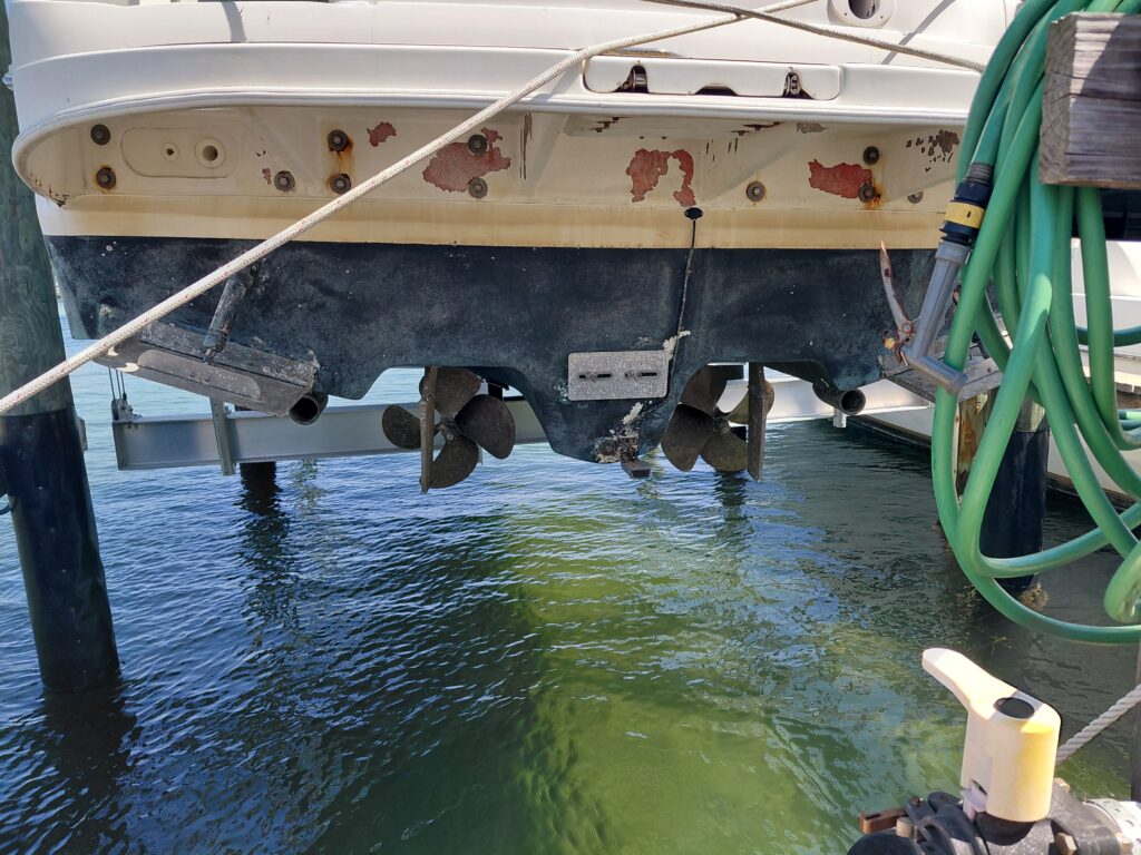 Stern and propellers of a boat supported above water beside a dock