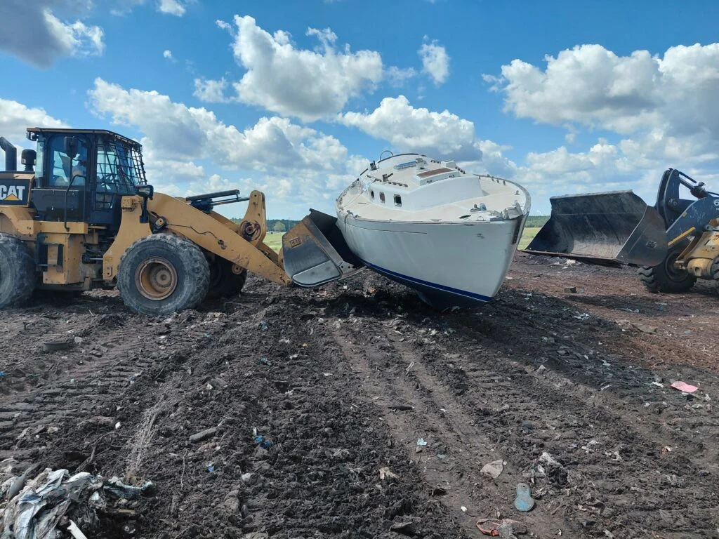 Sailboat hull on land between two wheel loaders