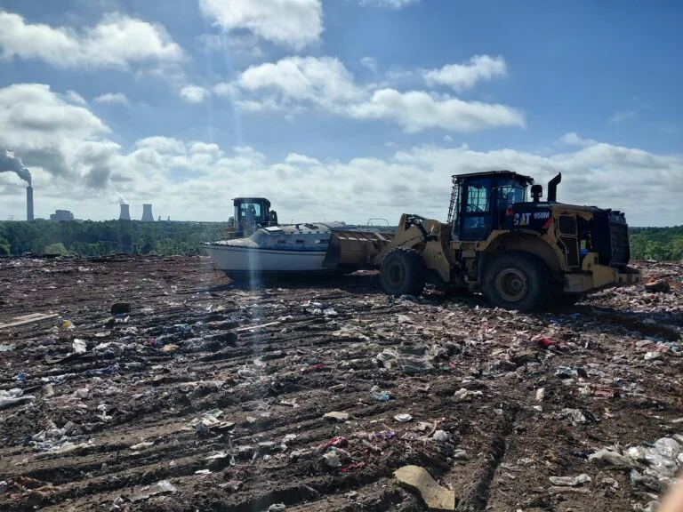 Boat beside a wheel loader at a disposal site